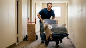 Ontario mover transporting wrapped furniture in hallway