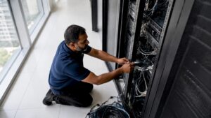 Technician disconnecting cables in server room