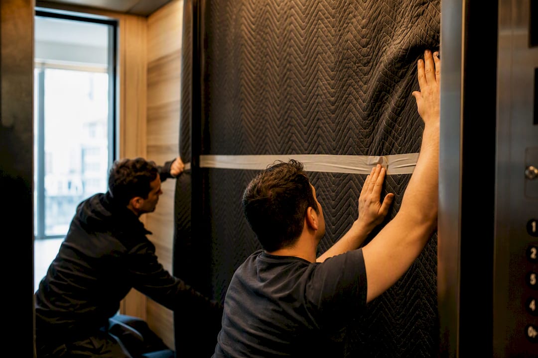 Movers applying padding inside condo elevator