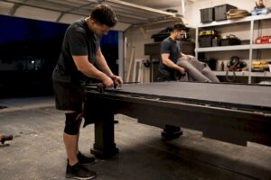 Movers disassembling pool table indoors
