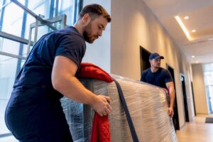 Movers transferring wrapped furniture through lobby