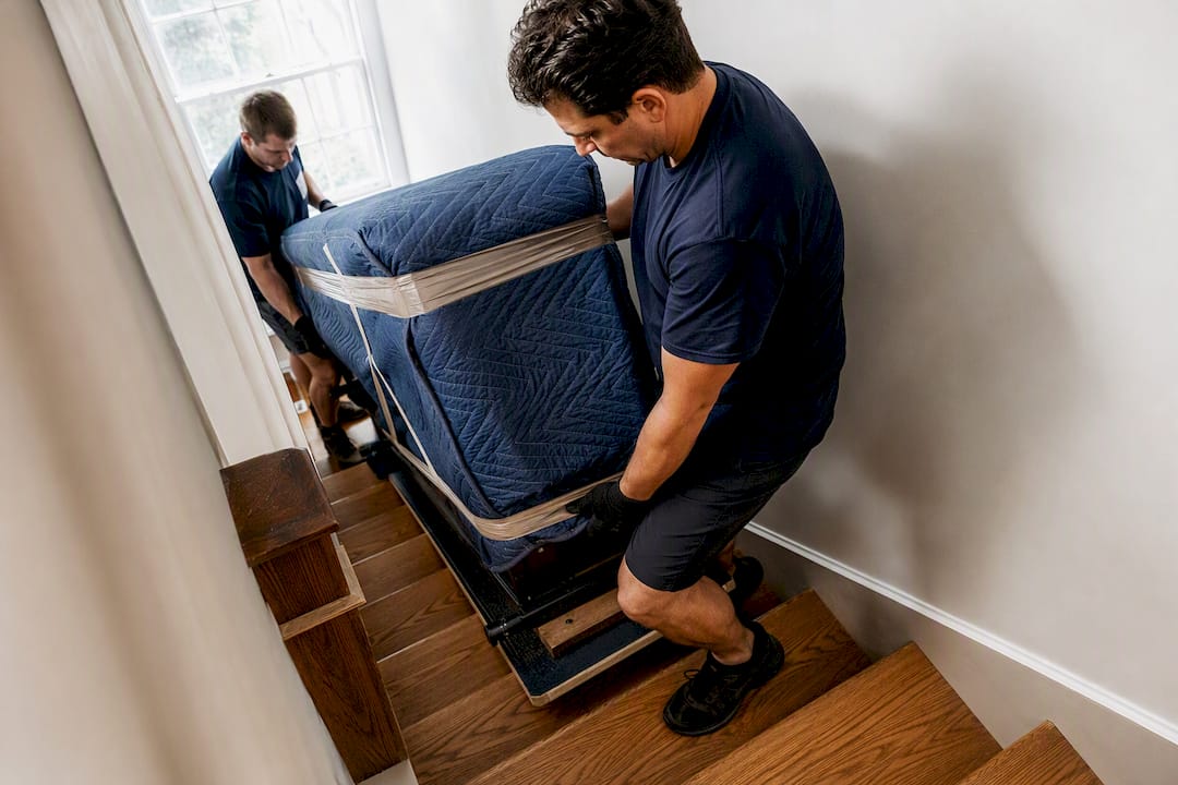 Crew carefully carrying padded piano downstairs