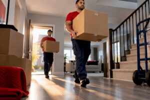 Movers carrying boxes through townhouse entry