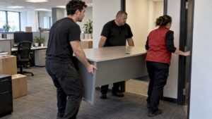 Three movers carrying a desk through an office